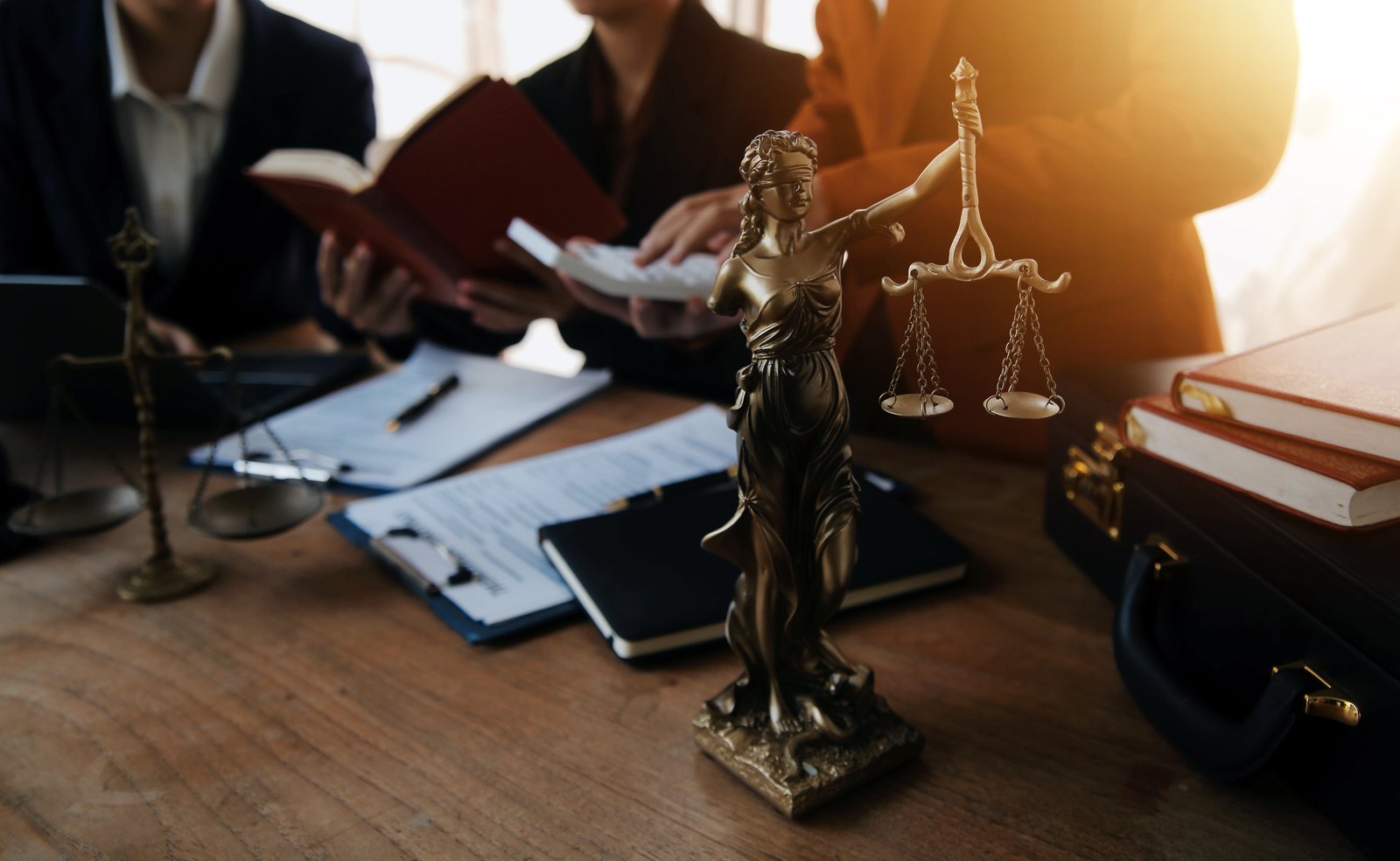 مجسم العدالة على مكتب مع فريق قانوني