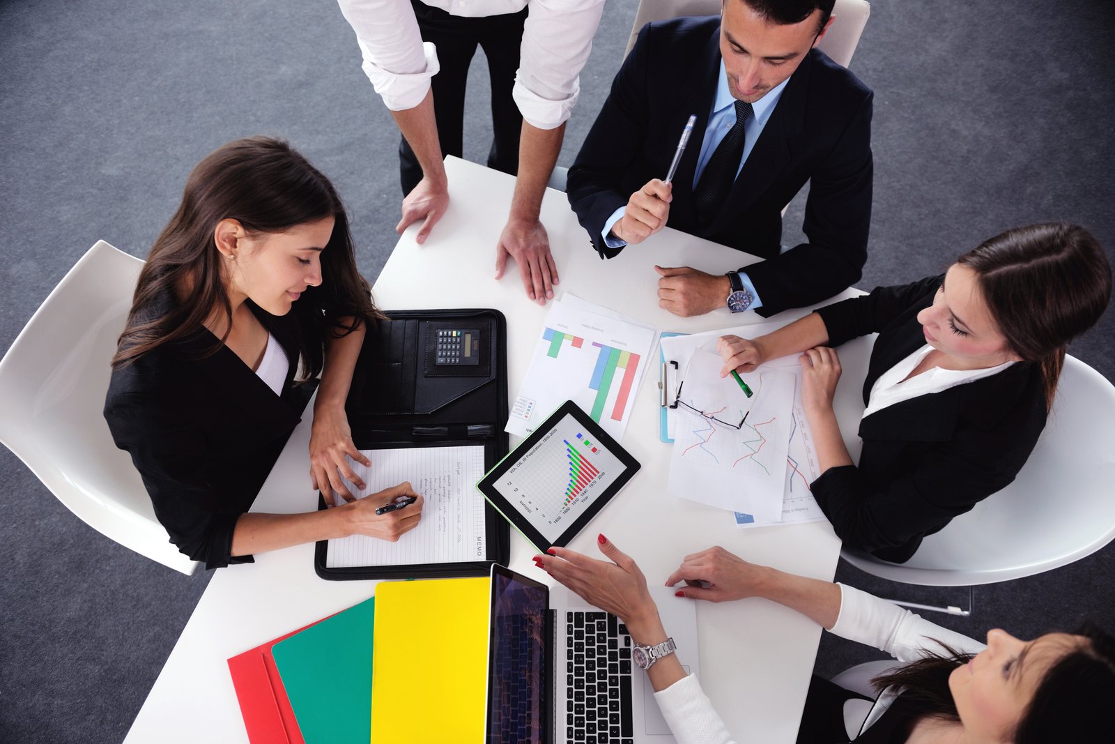 فريق عمل يجتمع حول طاولة مع مخططات وأجهزة